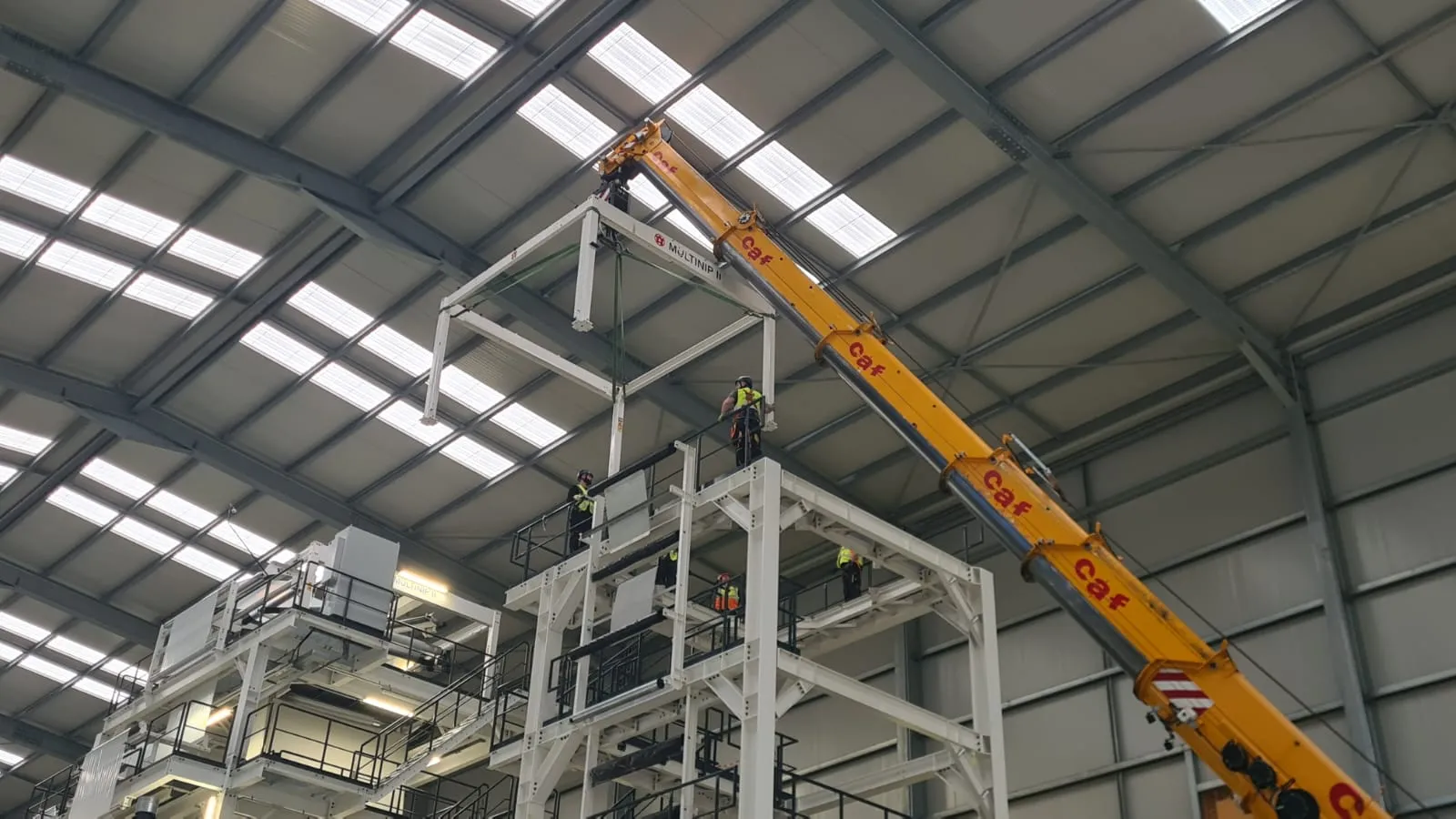 Crane lowering a steel frame onto industrial machinery