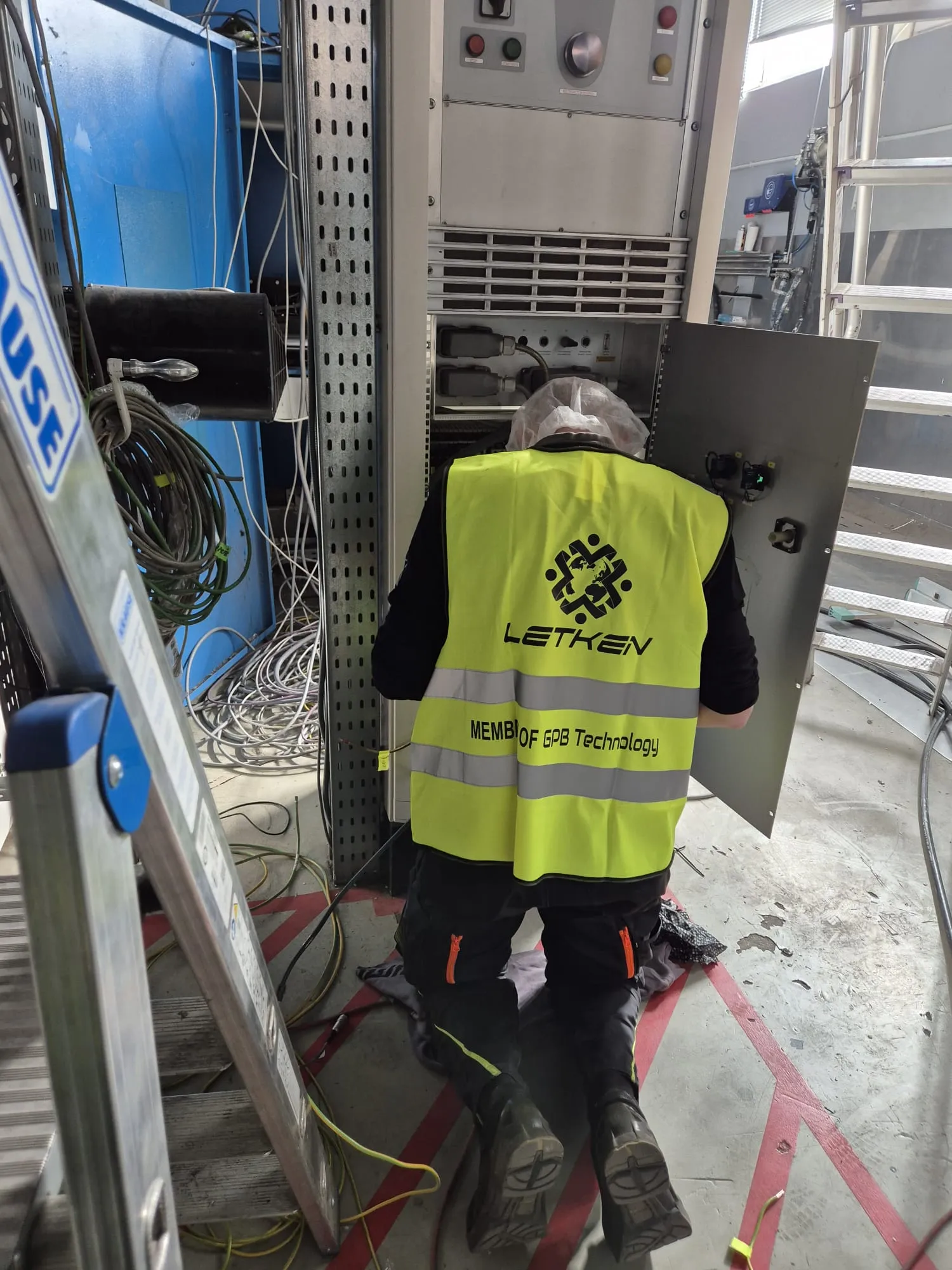 Technician working inside an open electrical cabinet